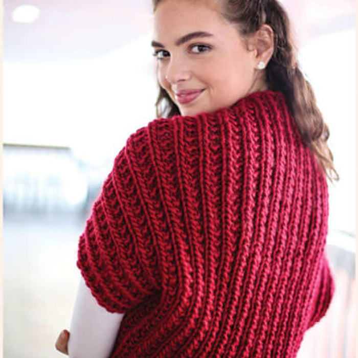 Woman wearing red shrug with textured rib pattern, crafted from Crucci Natural Wonder Artisan yarn.