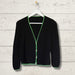 Simple black summer cardigan on hanger with green ribbed edges.