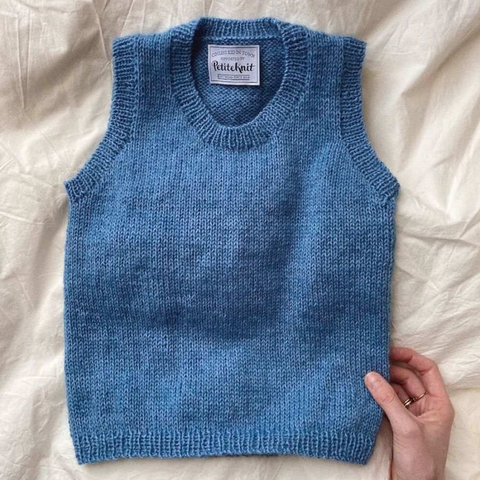 PetiteKnit Stockholm Slipover Mini in blue on beige fabric background.