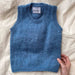 PetiteKnit Stockholm Slipover Mini in blue on beige fabric background.