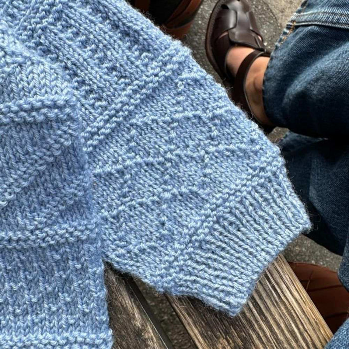 Close-up of the Storm Sweater Baby knit in a textured pattern using PetiteKnit pattern.