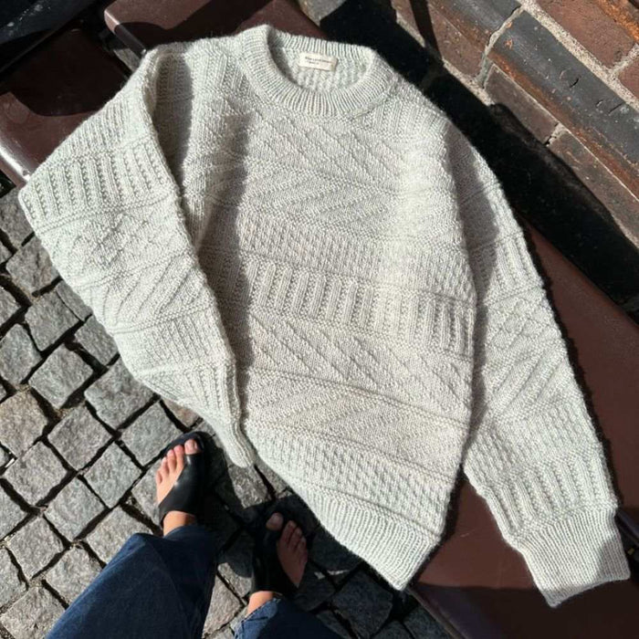 Storm Sweater on a bench in textured knit pattern with ribbed neckline and intricate detailing, designed by PetiteKnit.