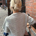 Back view of a woman wearing a Storm Sweater in a textured knitting pattern, showcasing the detailed yoke and ribbed neck edge, by PetiteKnit.