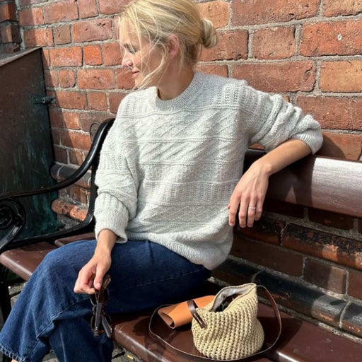 Storm Sweater Knitting Pattern by PetiteKnit, textured design, worn by person seated outdoors.