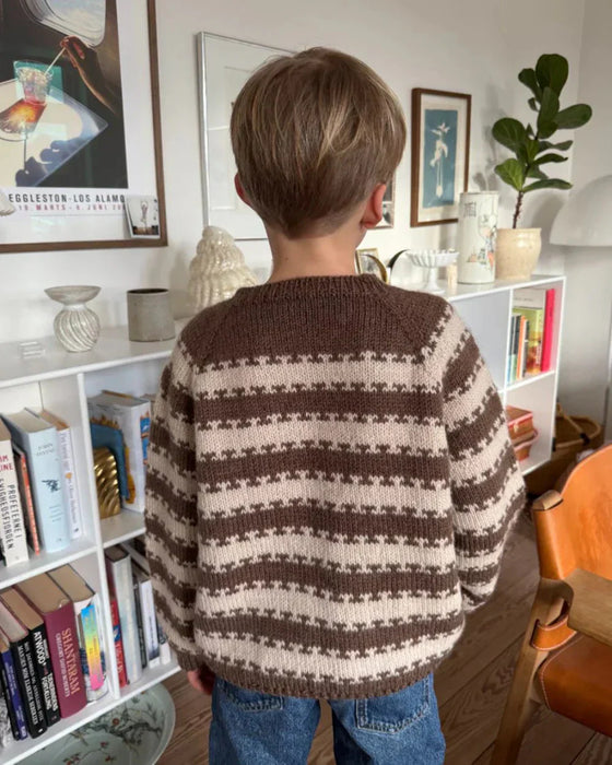 Junior wearing a two-color striped sweater, knit with PetiteKnit's pattern, displaying ribbed edges and a relaxed fit.