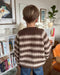 Junior wearing a two-color striped sweater, knit with PetiteKnit's pattern, displaying ribbed edges and a relaxed fit.