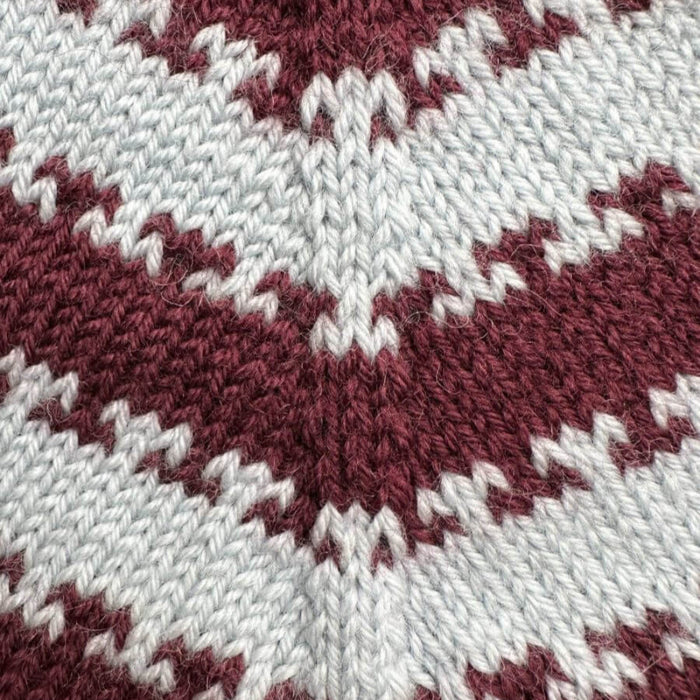 Close-up of a two-color striped knitting pattern in burgundy and light gray, used in the Key Sweater Junior by PetiteKnit.