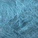 Luxuriously brushed 12-ply mohair yarn in a soft blue color, ideal for knitting projects.