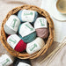Basket of Naturally Moro 12-ply yarn in various colors with knitting needles and coffee cup.