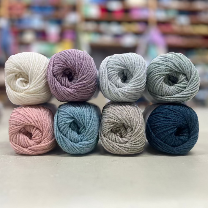Eight balls of 12-ply New Zealand Merino yarn in various colors displayed.