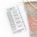 Quick Gauge ruler for measuring stitch gauge in knitting and crochet with multiple stitch count grids per inch next to knitted fabric and wooden knitting needles