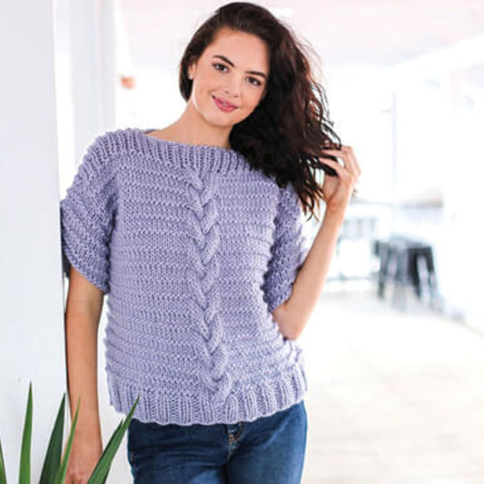 Woman wearing a stylish short sleeve knitted top with textured pattern and ribbed details, created using Crucci Natural Wonder Artisan yarn. Ideal knitting pattern for intermediate knitters.