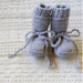 Flat lay of the pale grey textured baby hat and tied booties — Ari Hat and Booties, Lisa F BC142.
