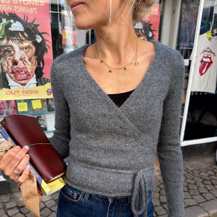 Lucy Wrap Knitting Pattern for a grey knitted wrap blouse with long ties and crossed front
