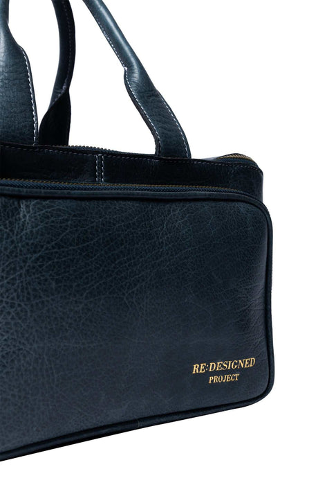 Sapphire blue Project 39 leather knitting project bag with front pocket, sturdy handles, detachable strap, and wide zip opening showing organized yarn and needles inside