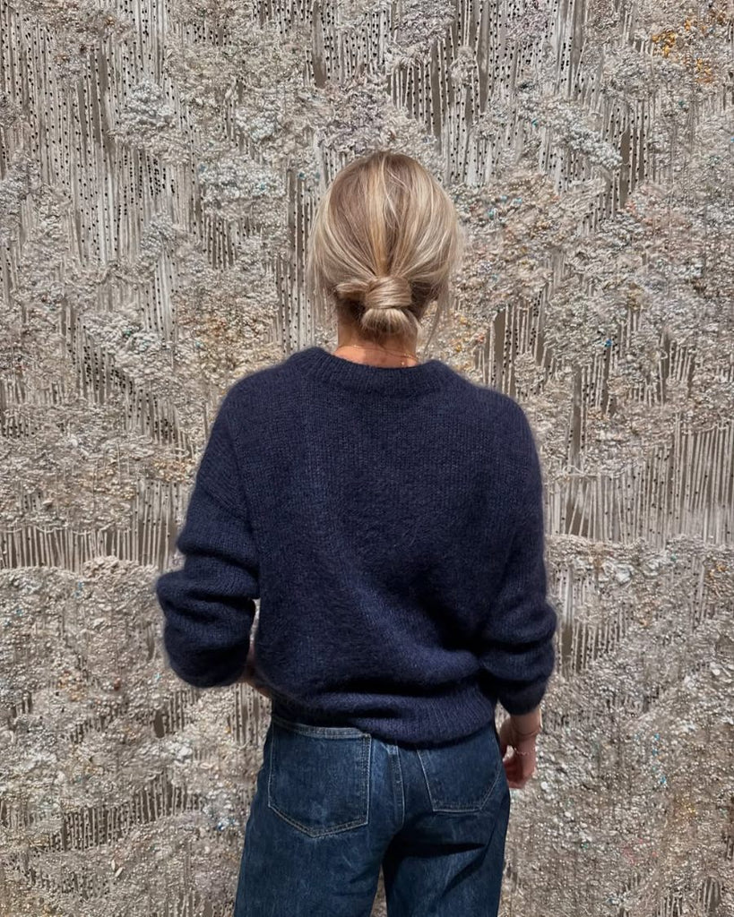 Back view of the navy blue Stockholm Sweater by PetiteKnit worn with jeans, showing the relaxed fit and dropped shoulders